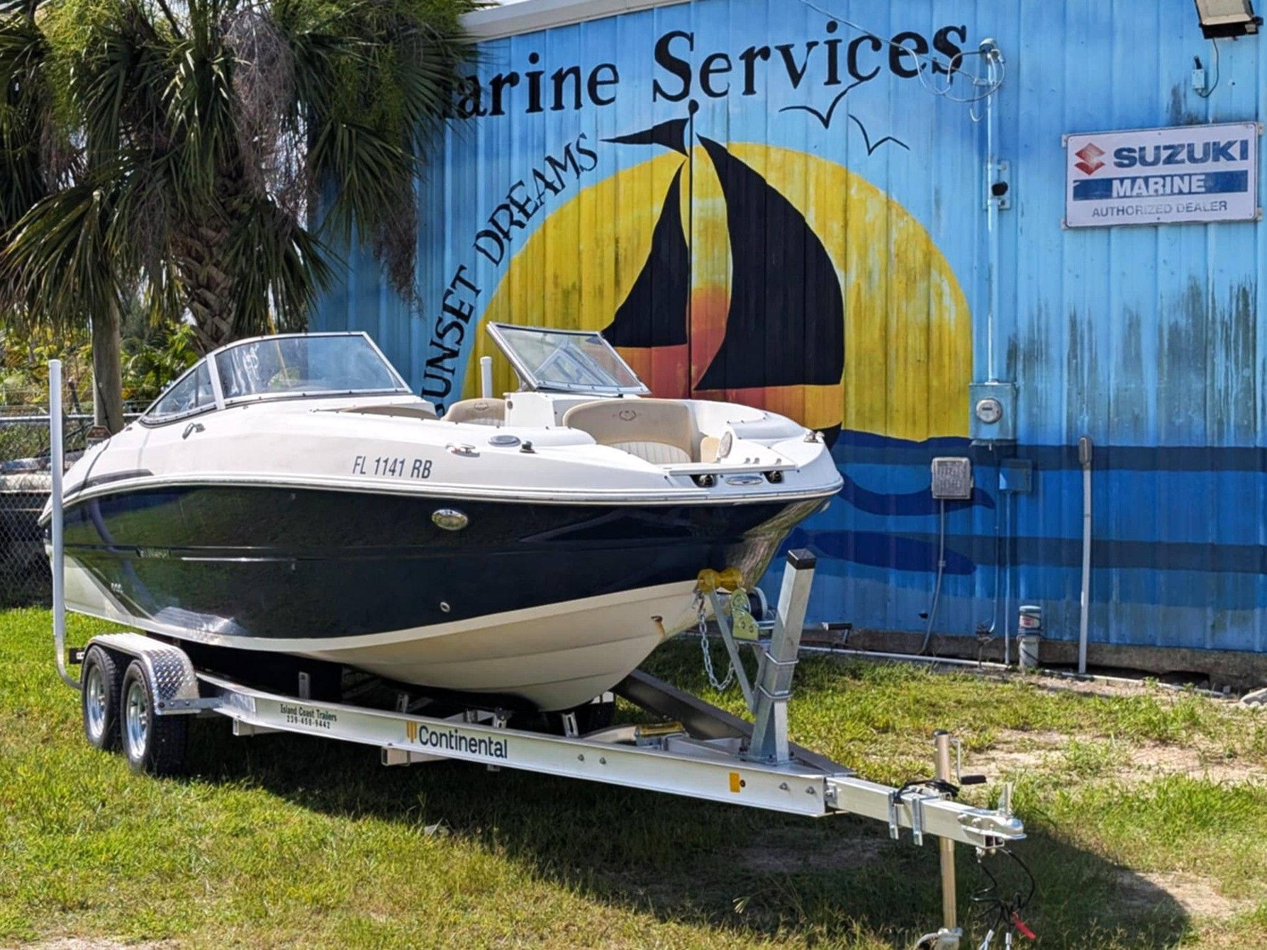 White and navy speedboat on a trailer in front of a blue marine services building
