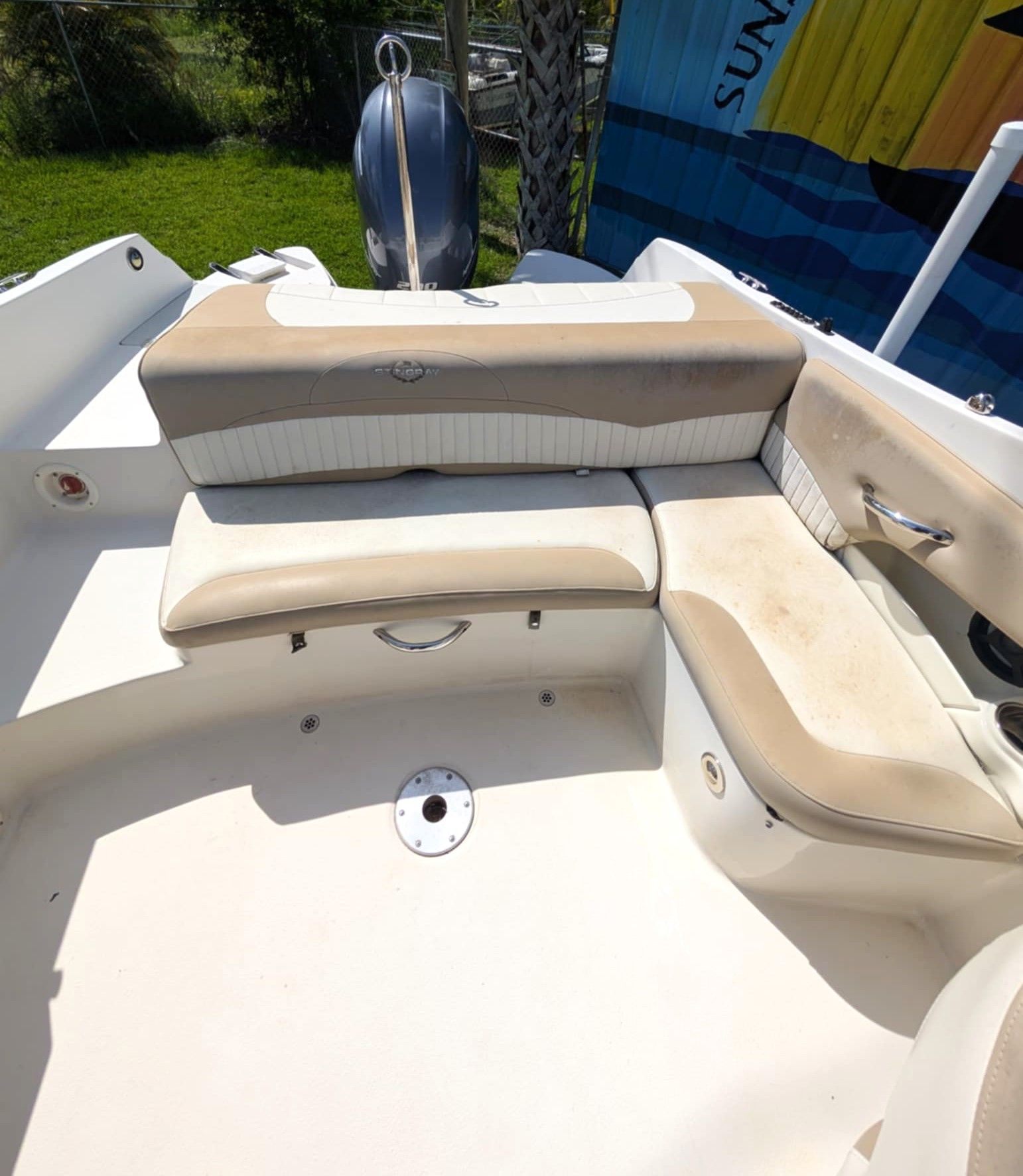 White boat cockpit with beige cushioned bench seating and a small center storage hatch.