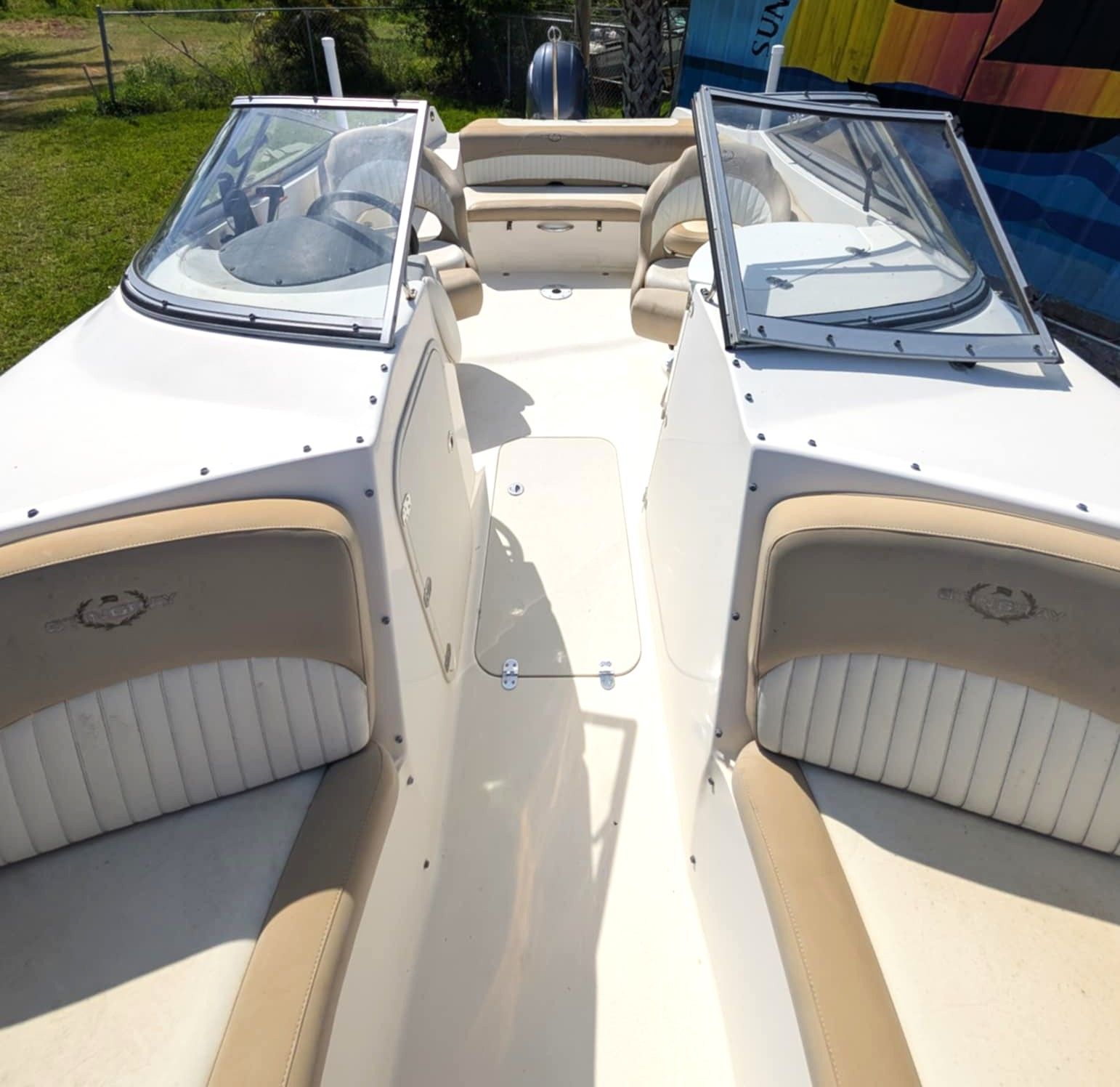 White boat interior with two cushioned seats and clear windshield, viewed from the center walkway.