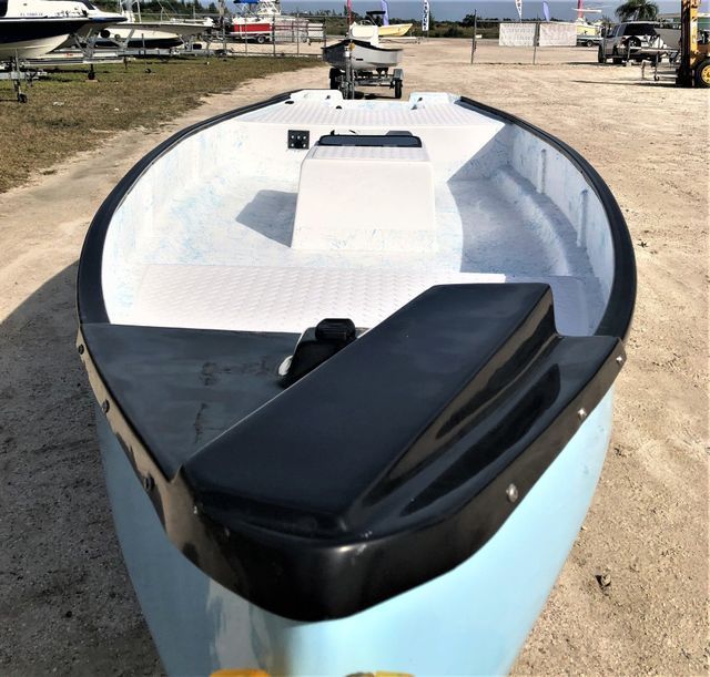A light blue boat with a black trim and white interior sits on a sandy lot.