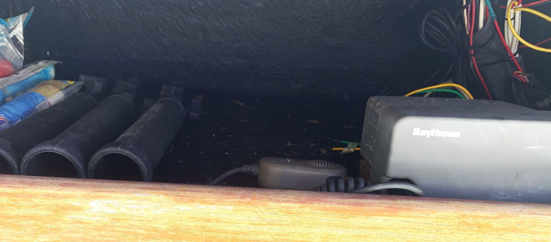 Dark car trunk with a gray cylindrical device, coiled hoses, and wiring inside.