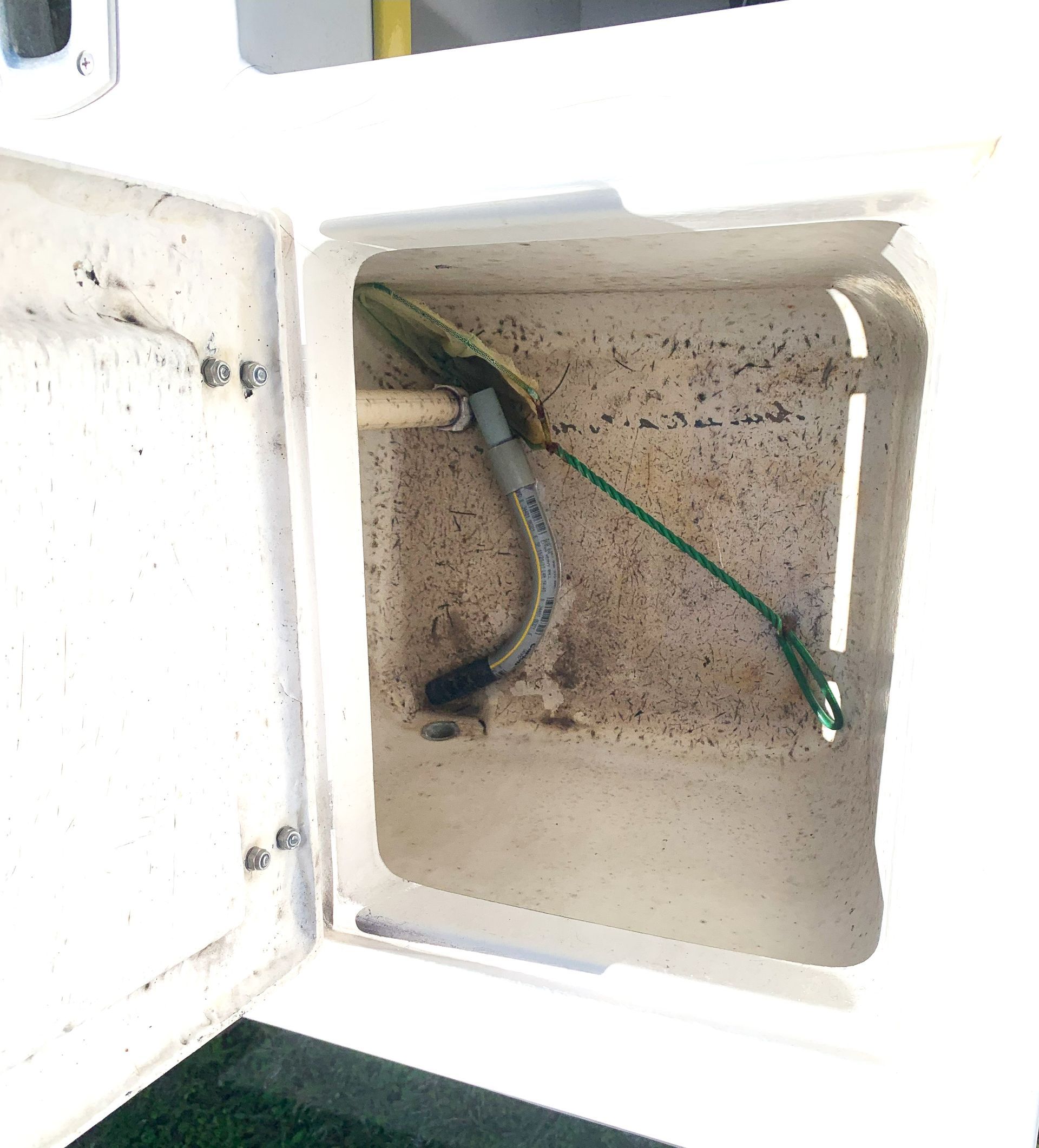 Open white electrical box with green and black wires inside against a dusty interior wall.