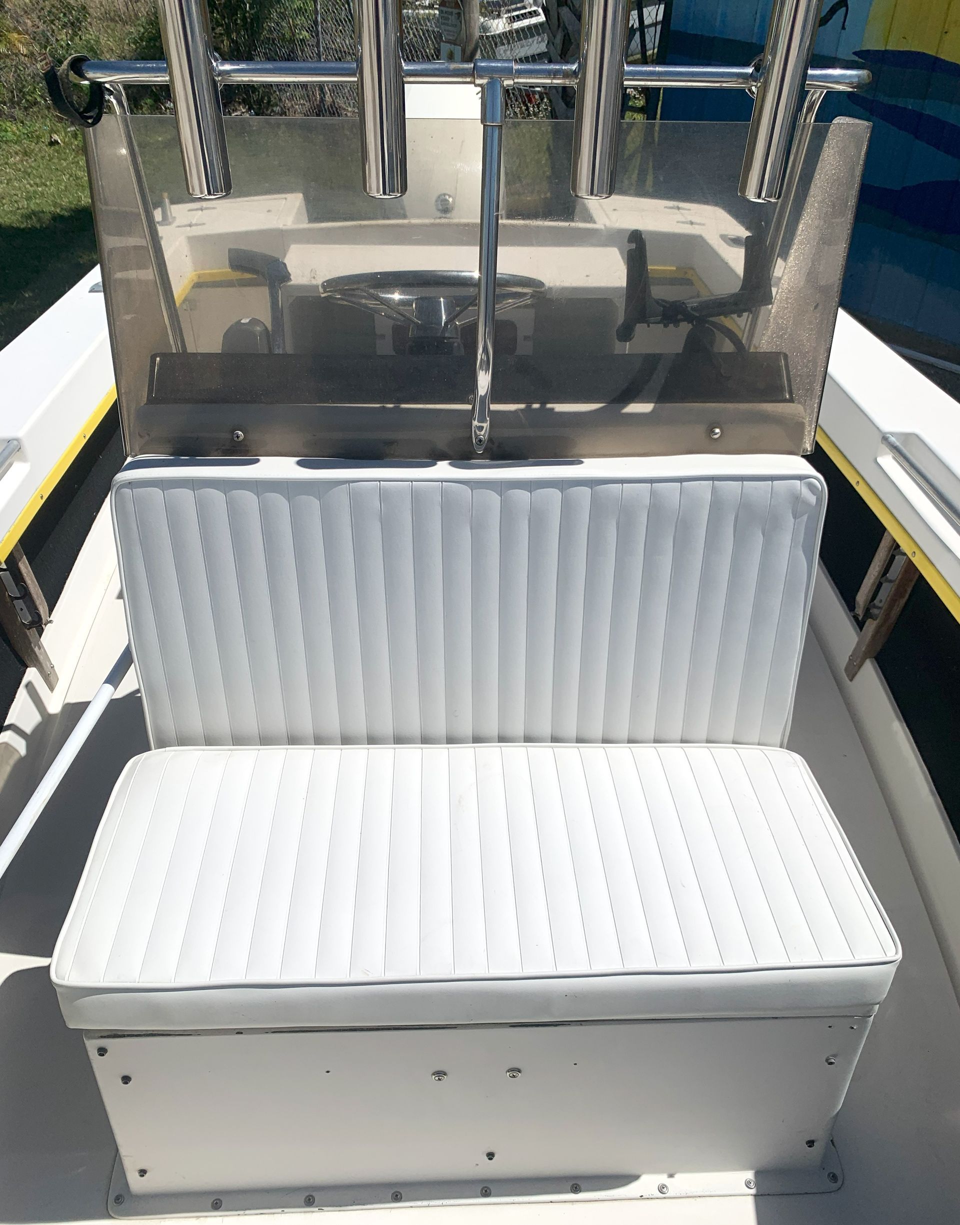 Open white padded machine seat beneath metal clamps and rails