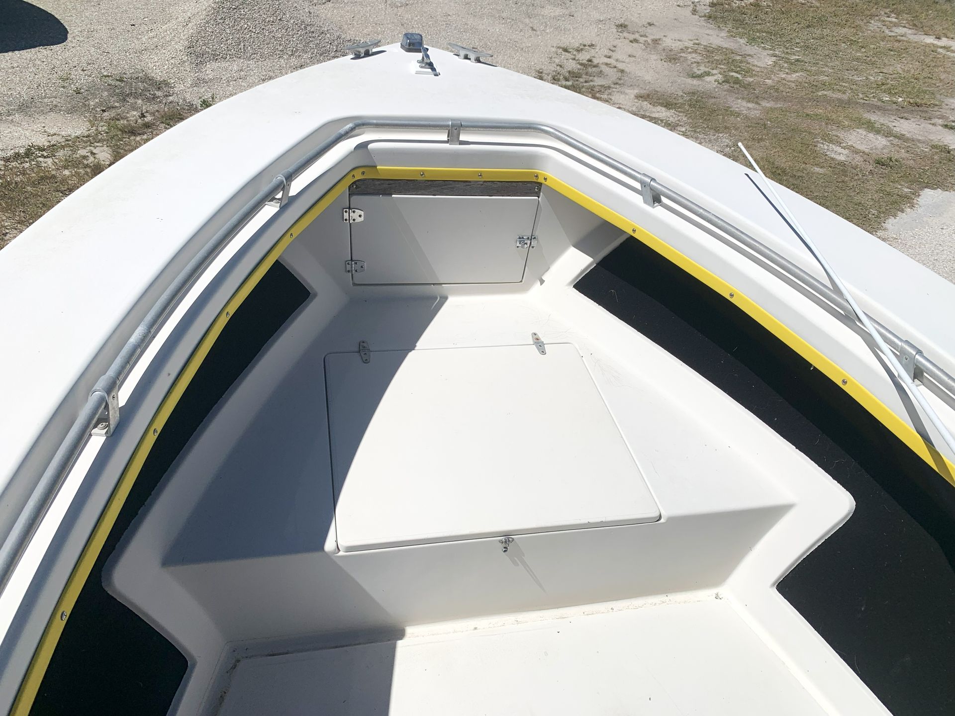 Empty white boat cockpit with built-in seating and dark floor viewed from above