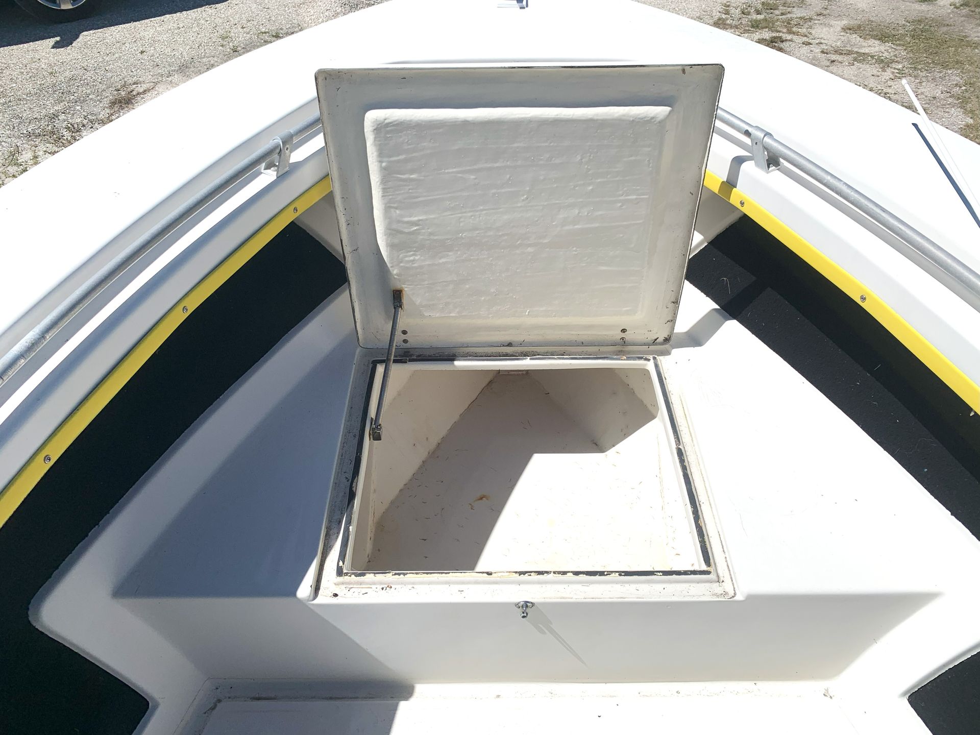 Open hatch on a white boat deck, showing a storage compartment below.