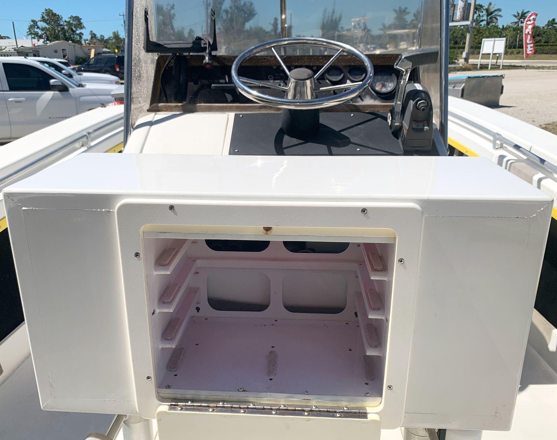 Open boat console with steering wheel and empty storage compartment in front of seating area
