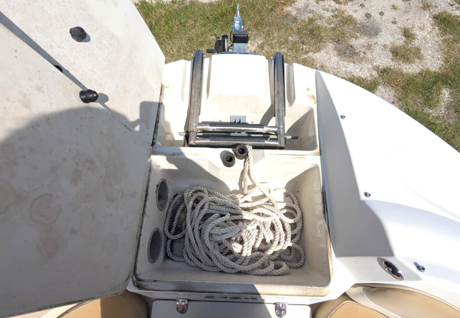 Coiled rope in a boat storage compartment beside a winch and deck hatch
