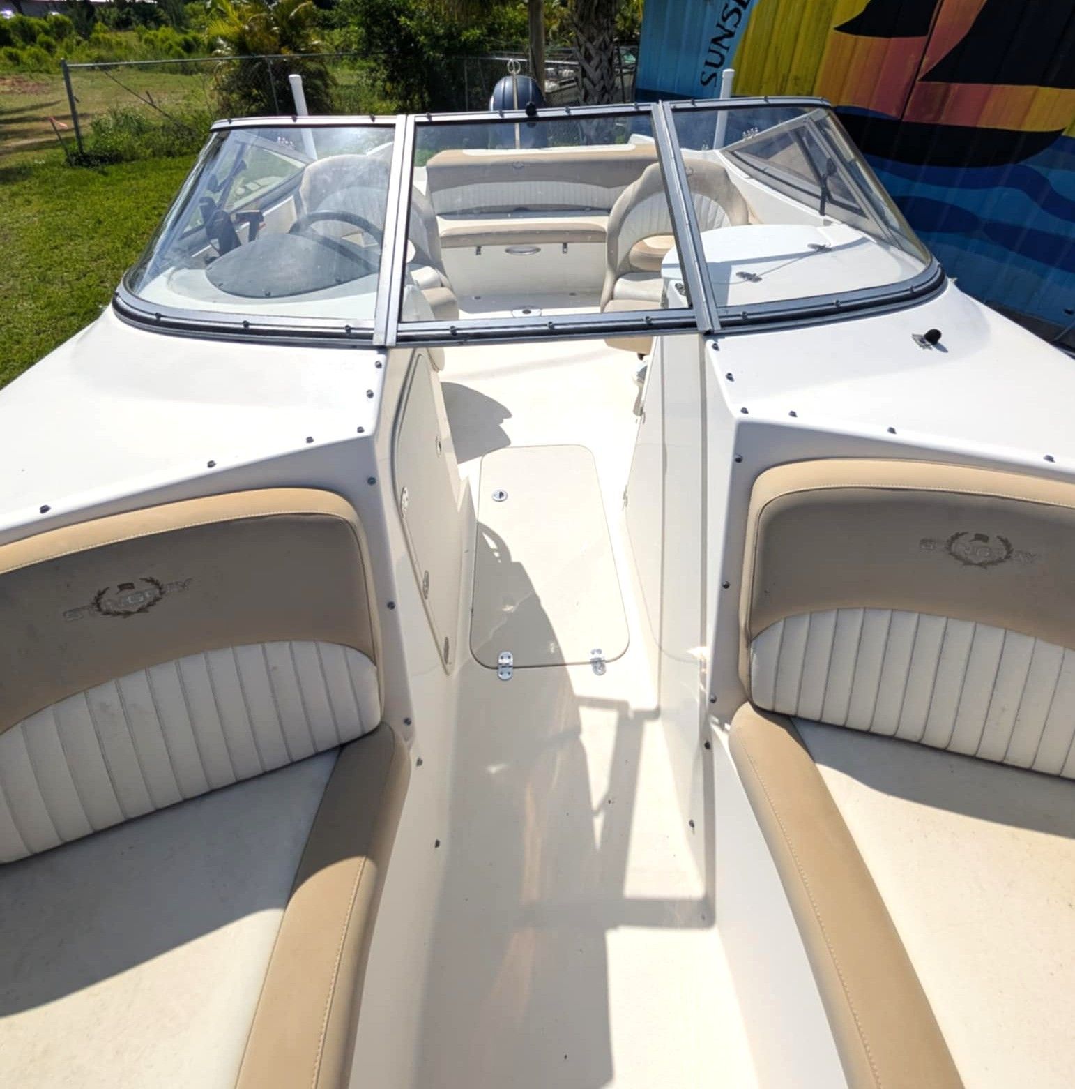 White boat cockpit with beige cushioned seats and a clear windshield in bright sunlight