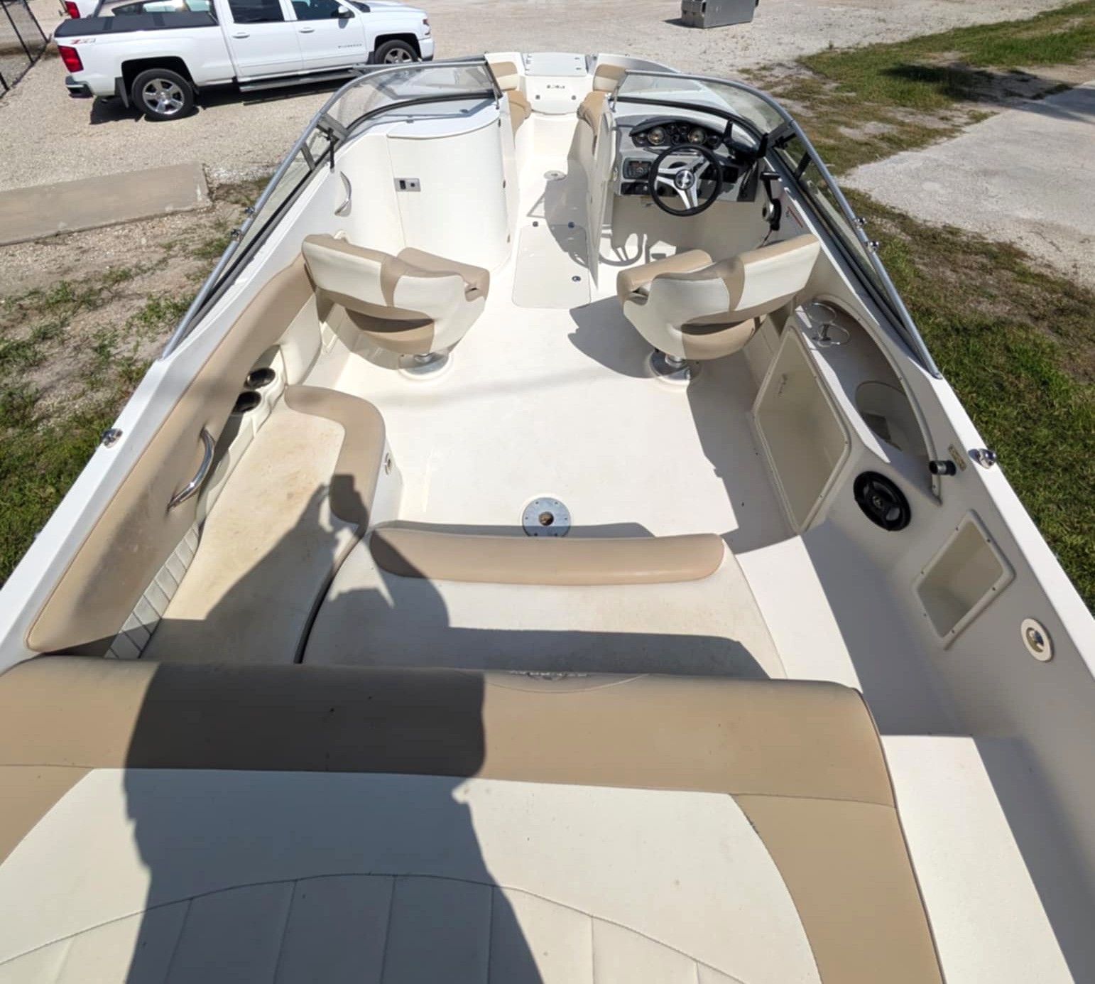 Interior of a small cream-and-tan boat with seats and steering wheel, viewed from the stern toward the bow.