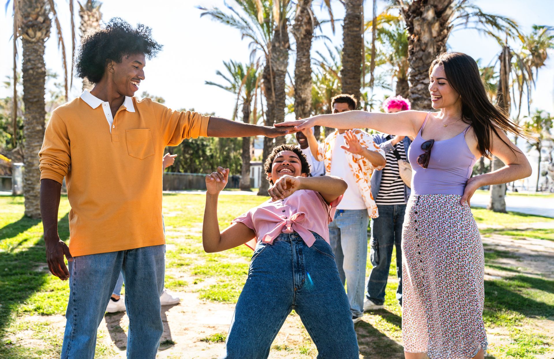 People posing outdoors in a sunny park, smiling and playing with colorful props