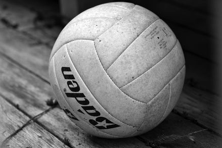 White volleyball resting on a wooden floor in black and white