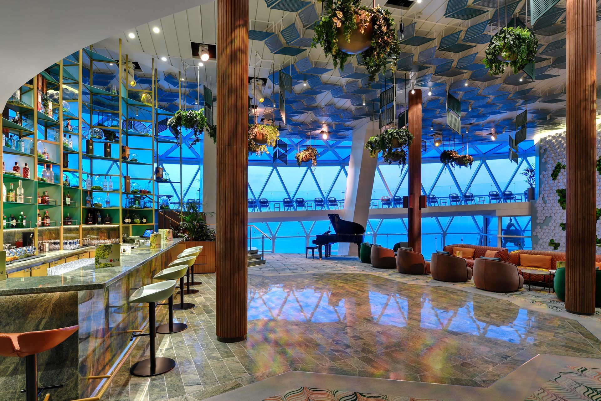Bar interior with marble floors, bar stools, drinks, and a grand piano, overlooking a blue outdoor view.