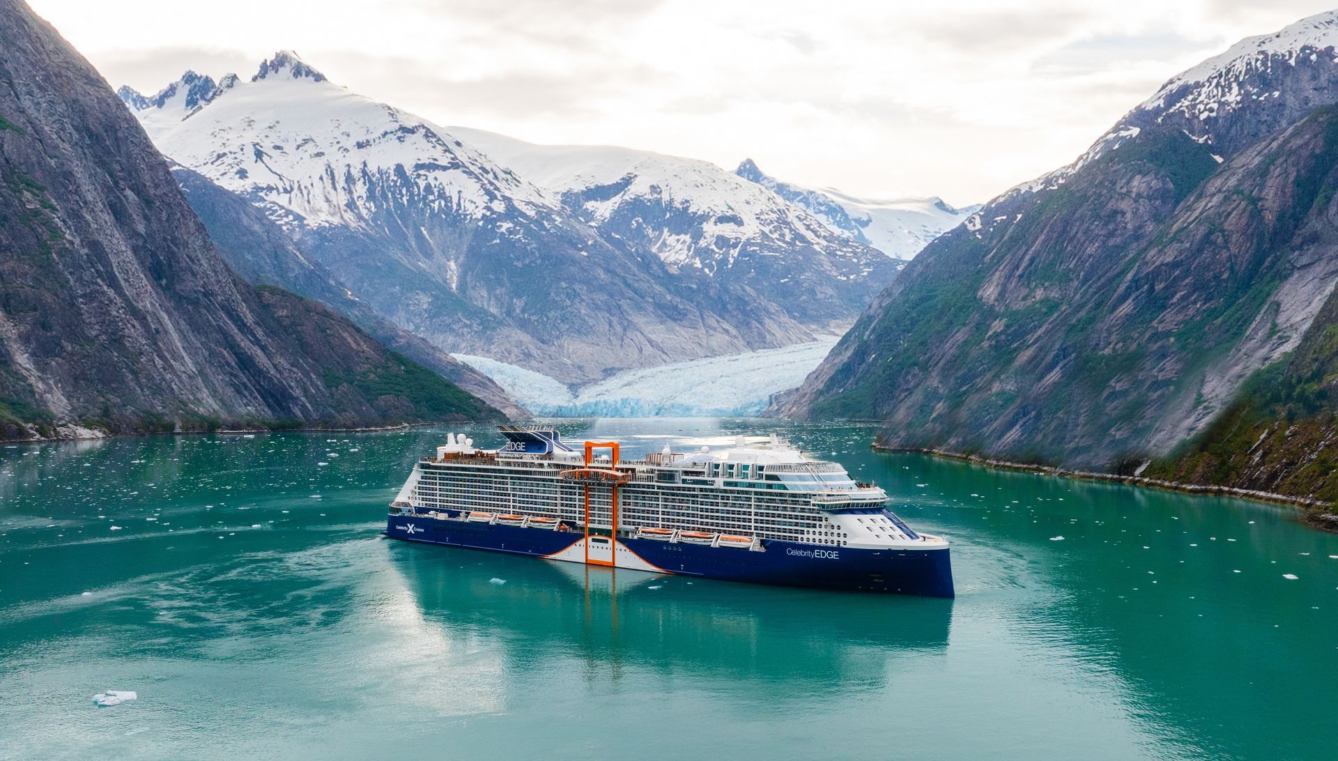 Cruise ship in turquoise water, glacier and mountains in background.