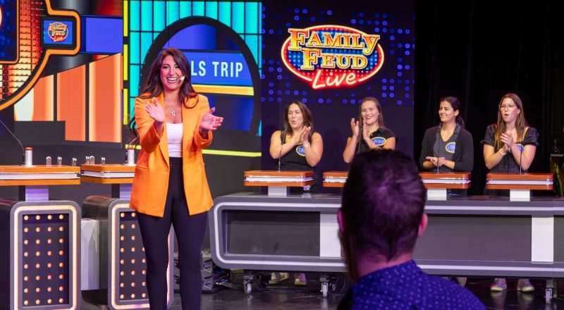 A woman in an orange blazer claps on a