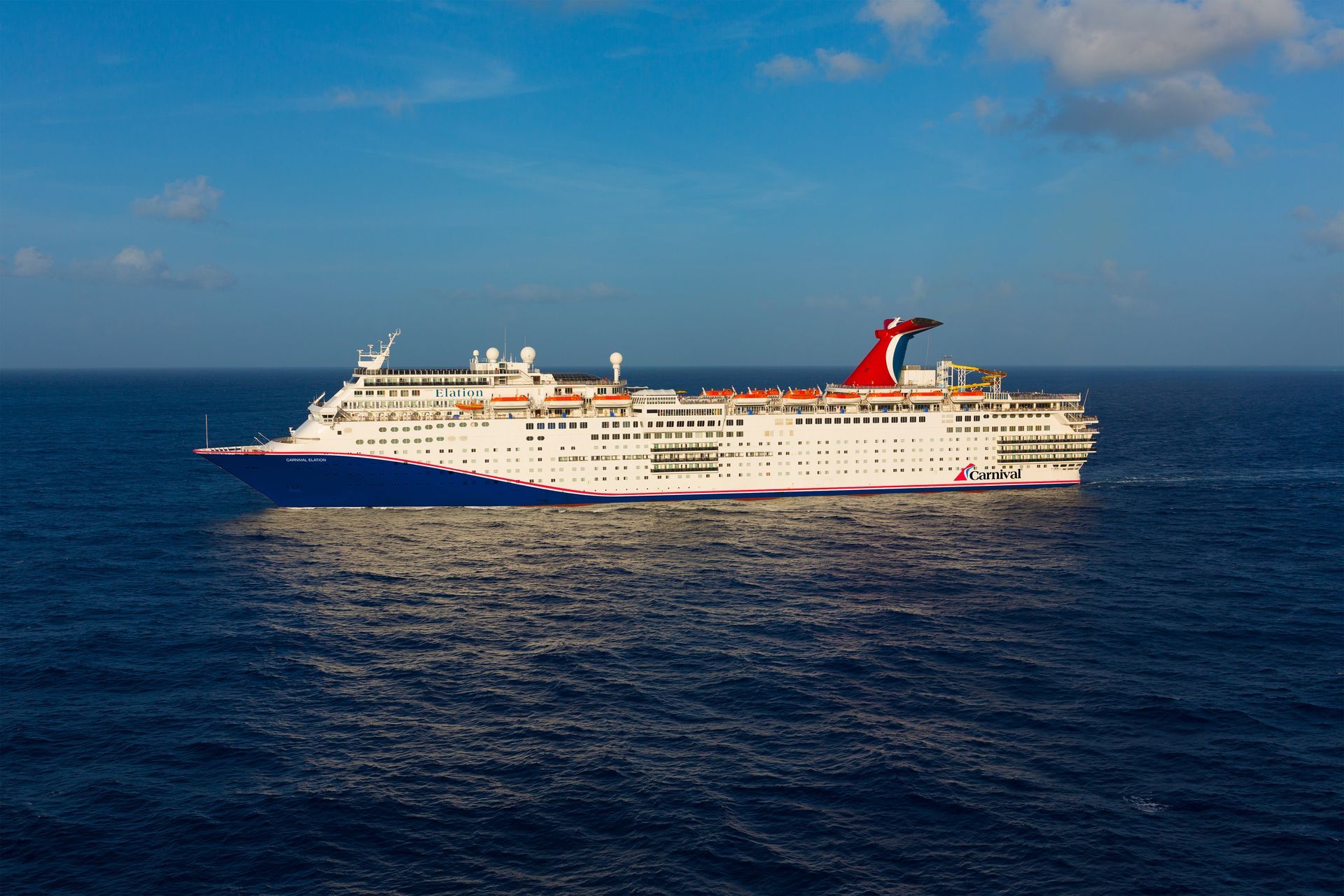 Cruise ship sailing on blue water under a clear blue sky.