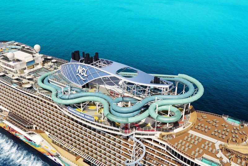 Aerial view of a cruise ship with water slides, a blue ocean, and a sunny day.