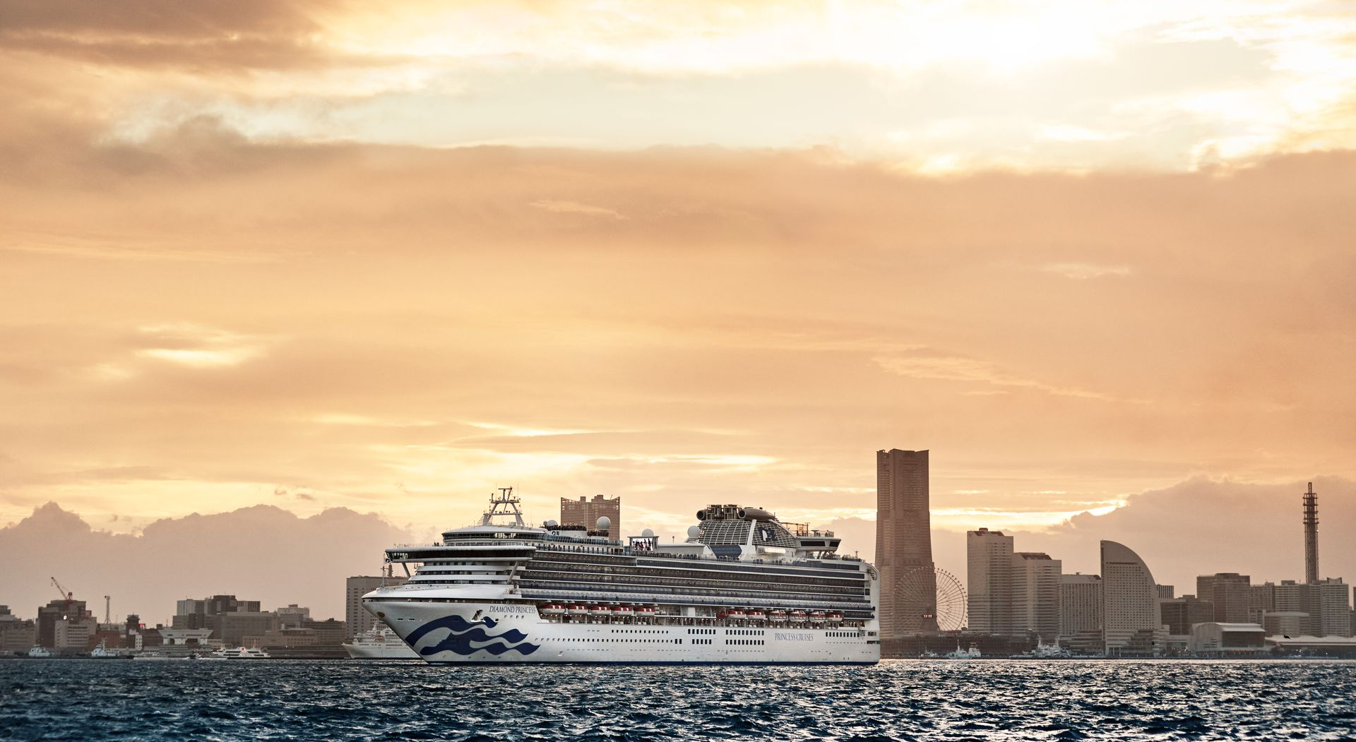Cruise ship near a city skyline at sunset.