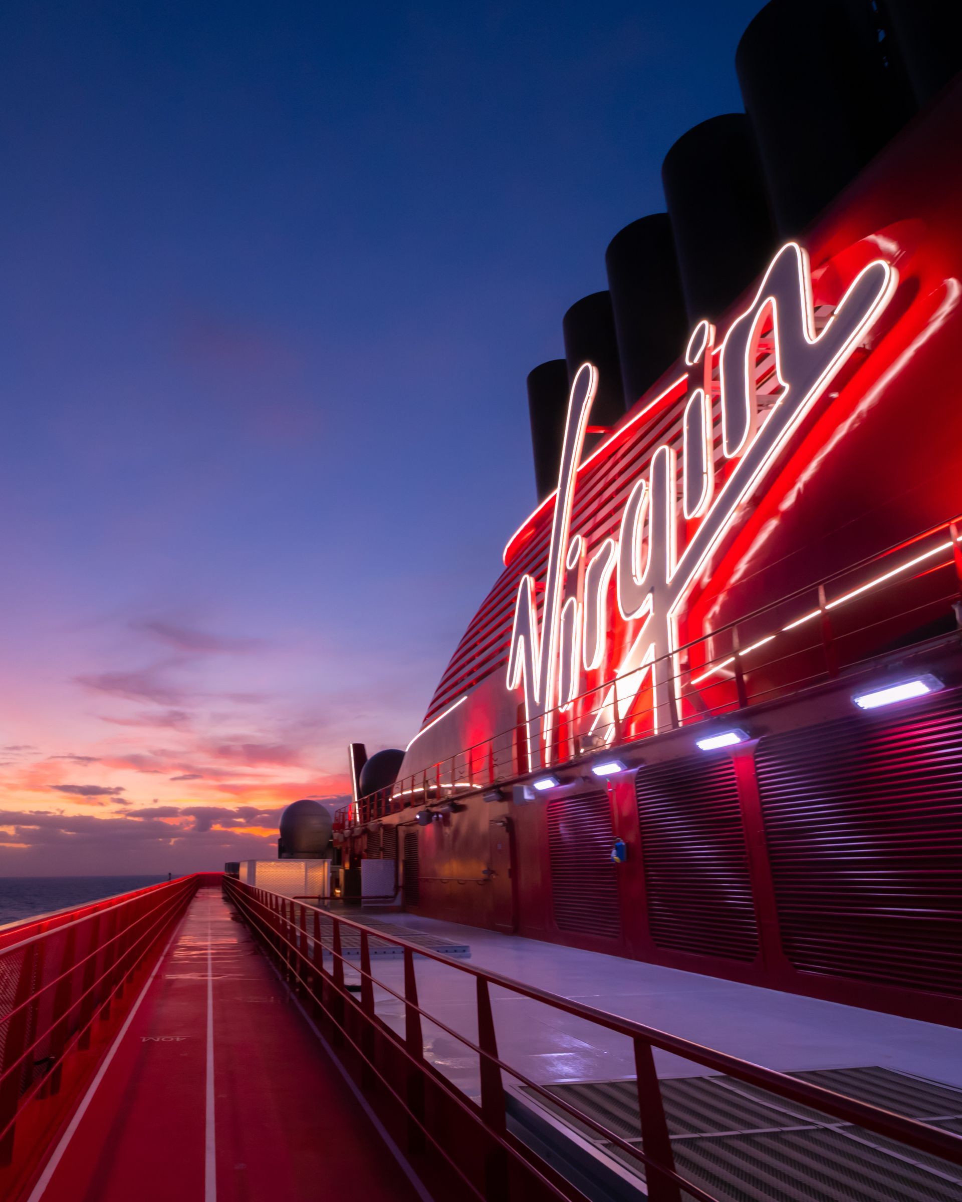 Red Virgin Voyages cruise ship logo illuminated at dusk.