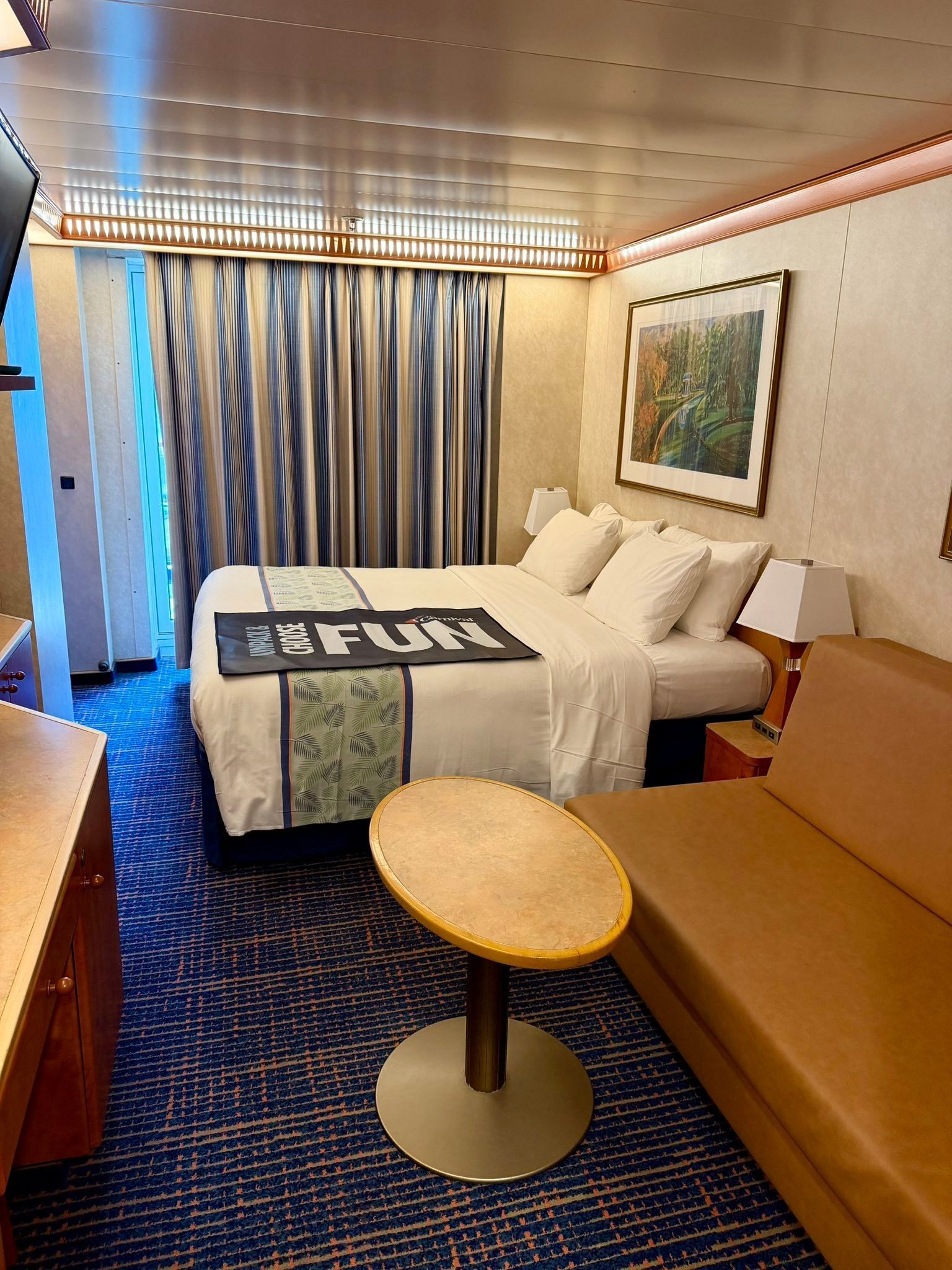 Elegant cruise ship stateroom with a king bed, warm wood paneling, and large windows with ocean views