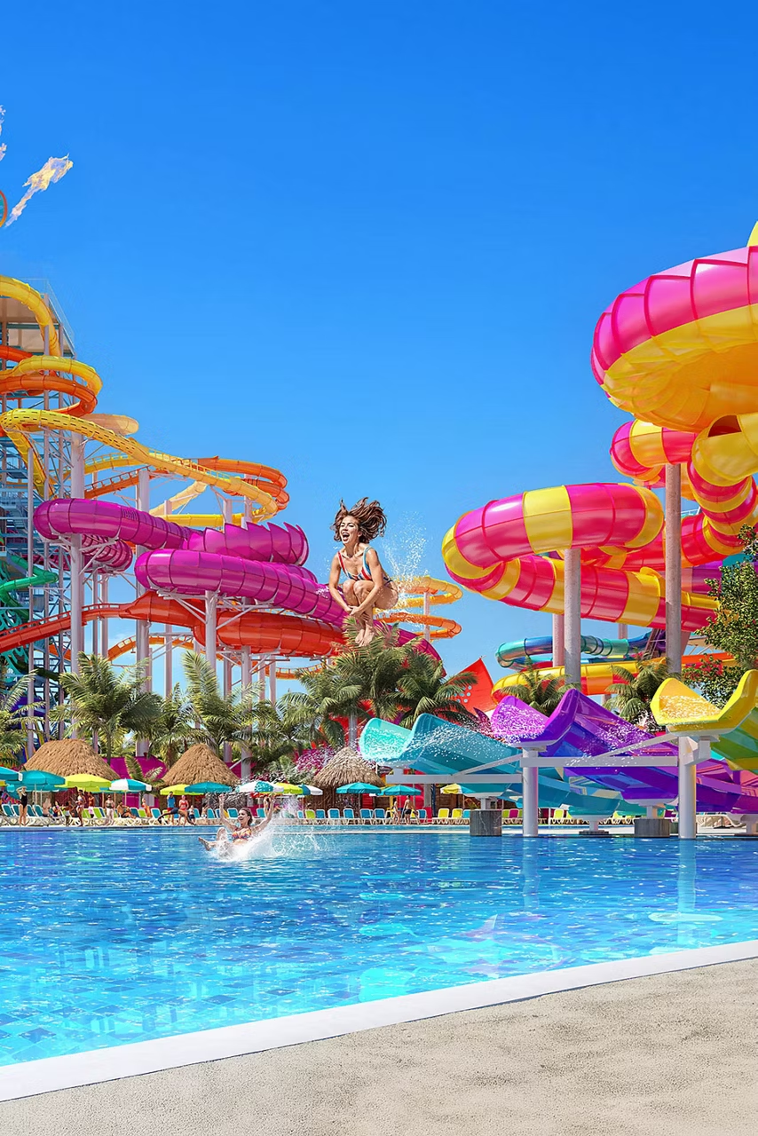 Water park with colorful slides and splash pool; a person is splashing in the water.