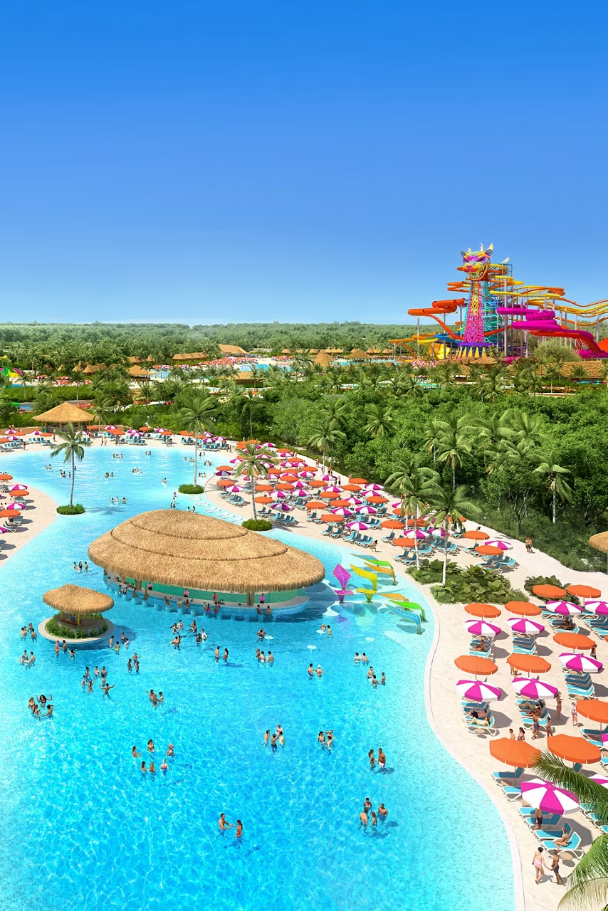 Aerial view of a waterpark with people swimming in a large pool and slides in the background.