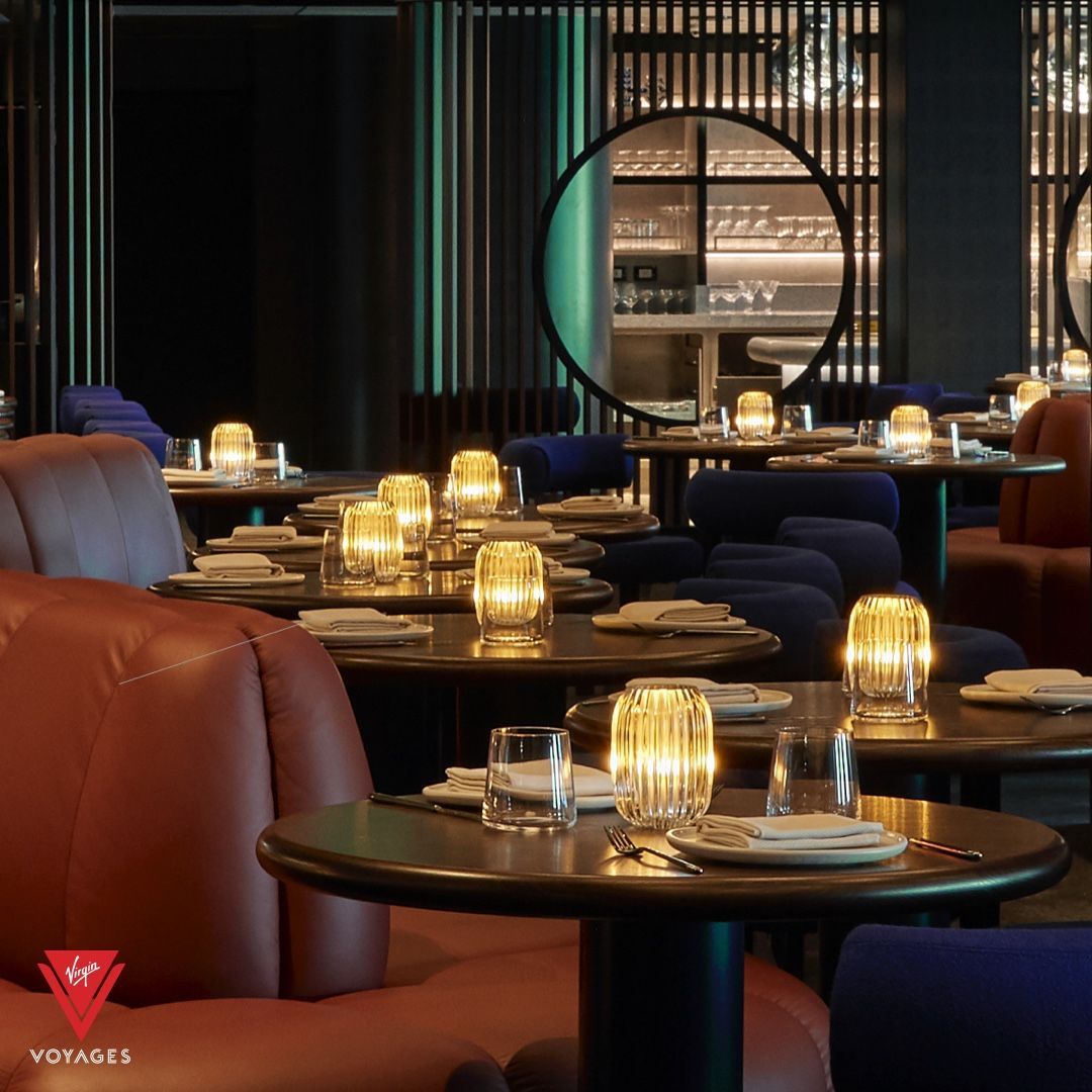 Elegant restaurant interior with round tables, leather booths, and dim lighting.