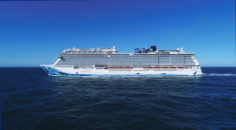 Cruise ship on a blue sea under a clear sky. The ship is white and blue.