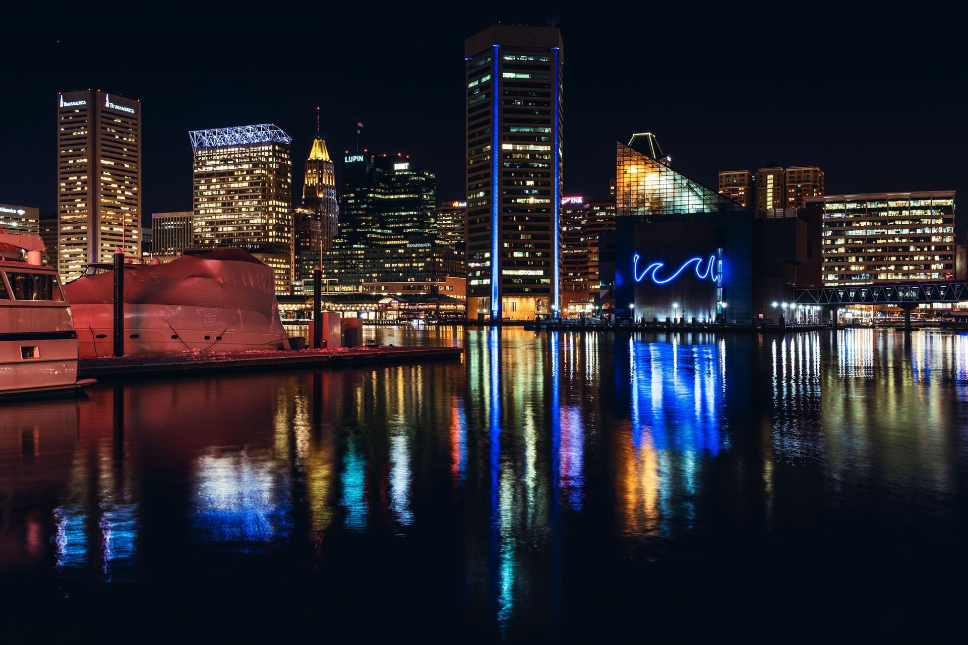 Nighttime city skyline with colorful lights reflecting on calm water.