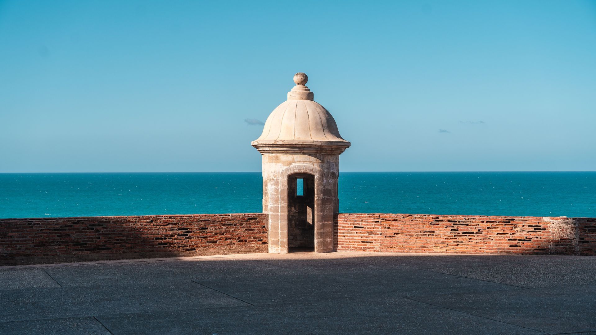 Small stone lookout tower by the sea under a clear blue sky