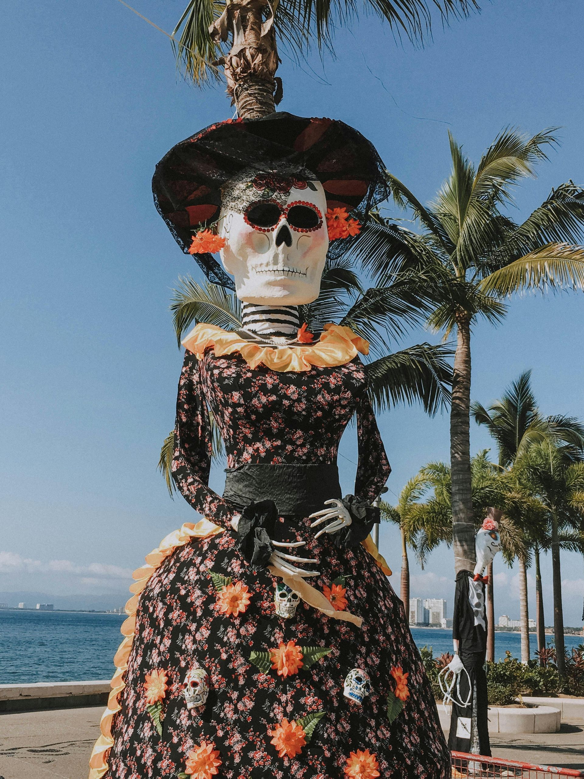 Skeleton in a floral dress and hat by the seaside, with palm trees and blue sky in the background
