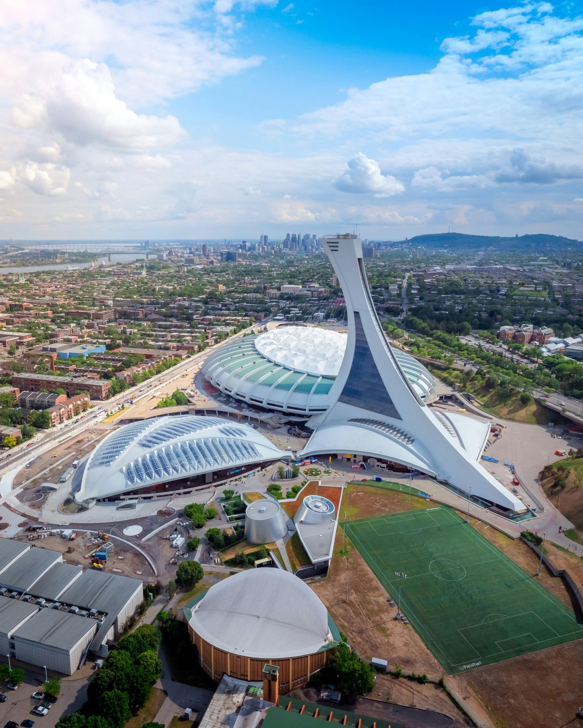 Montreal Olympic Stadium complex with a tall, white inclined tower against a blue sky.