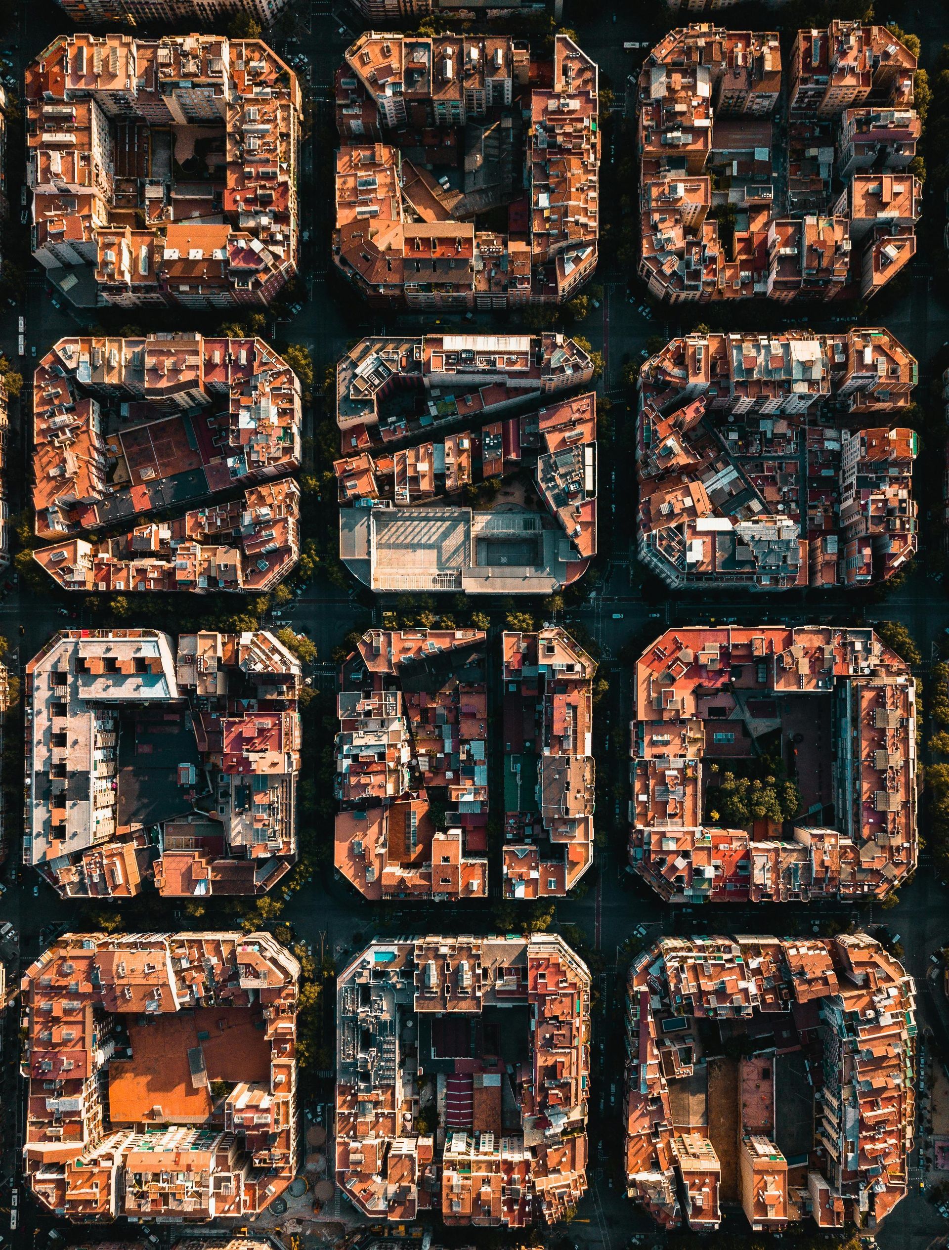Aerial view of square city blocks in Barcelona, with buildings in shades of brown and green streets.