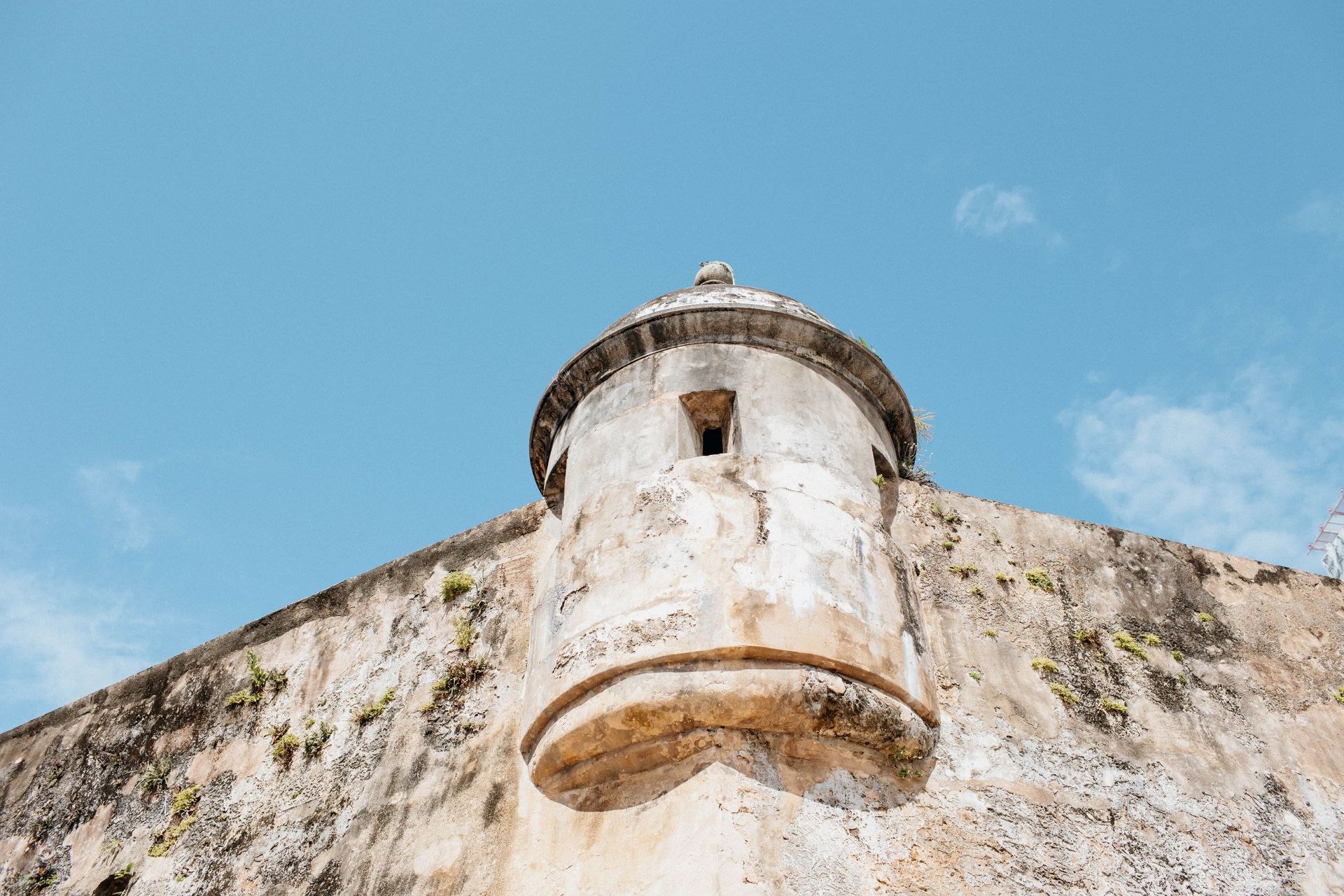 Stone fort tower against a bright blue sky, seen from below.