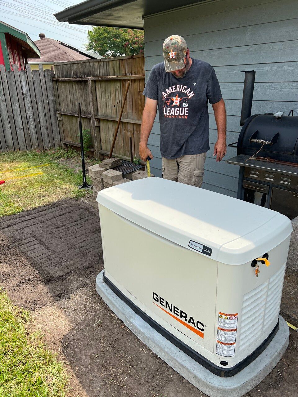 A man is standing next to a generator in a backyard.