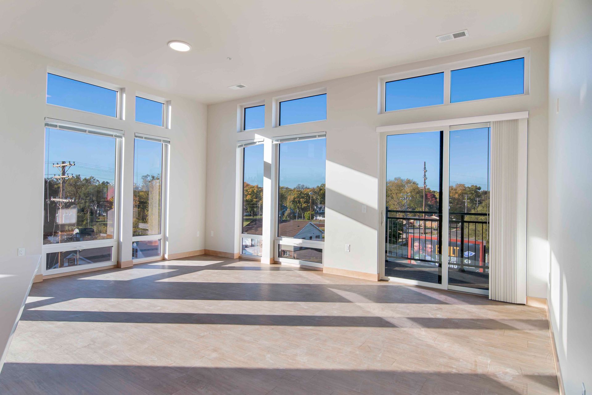 An empty living room with lots of windows and a balcony.