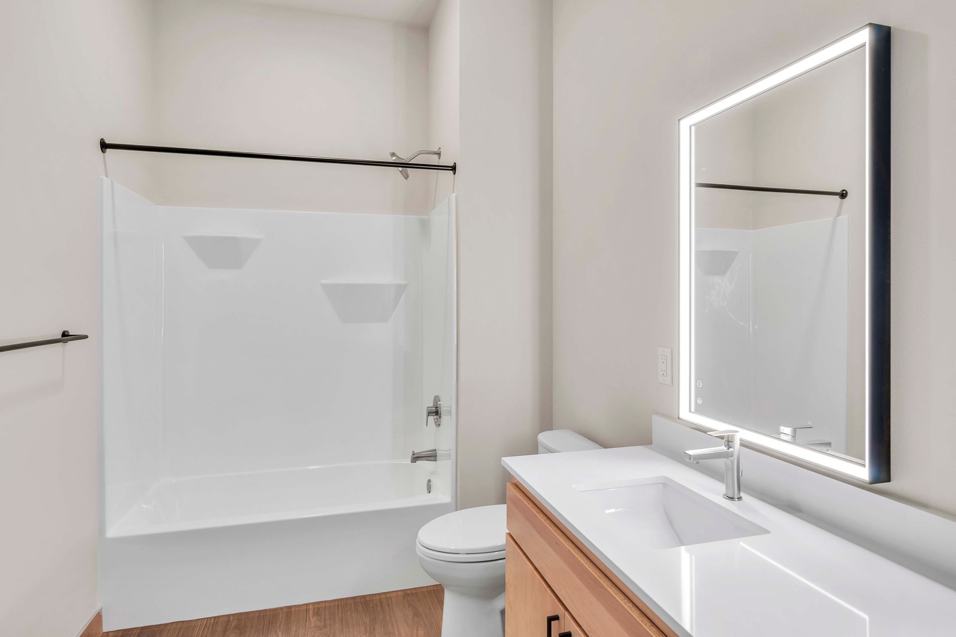 A bathroom with a sink , toilet , shower and mirror.