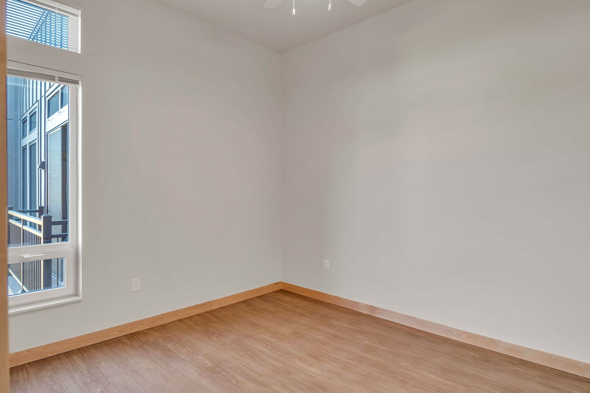 An empty room with hardwood floors and a window.