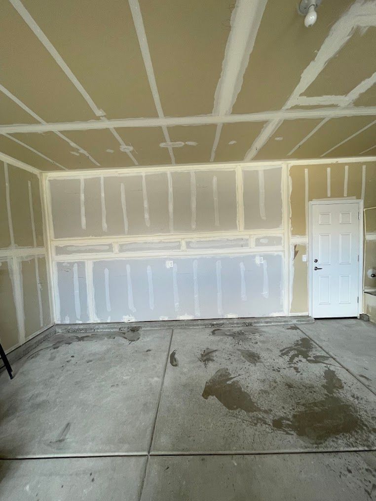 A bathroom under construction with a walk in shower and a door leading to another room.