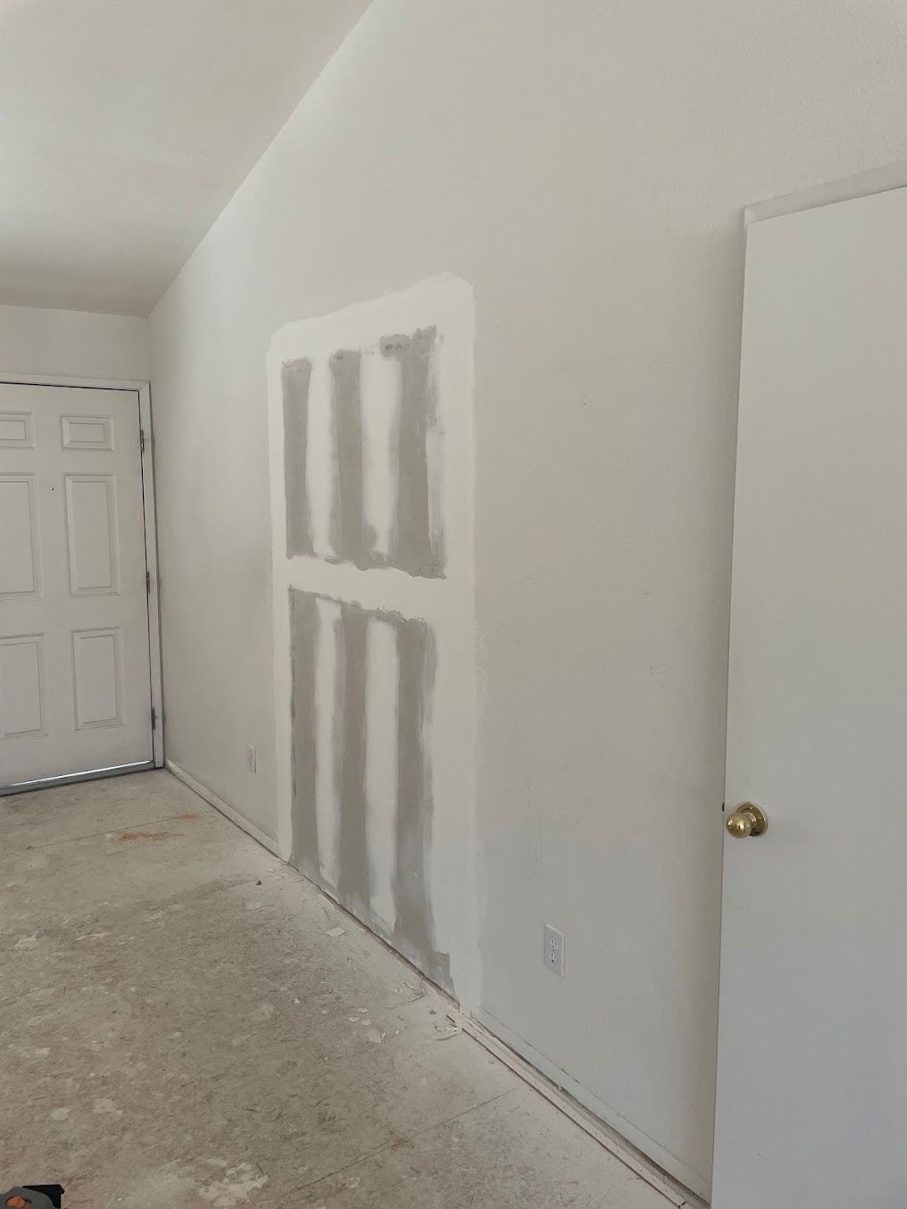 A bathroom under construction with a walk in shower and a door leading to another room.