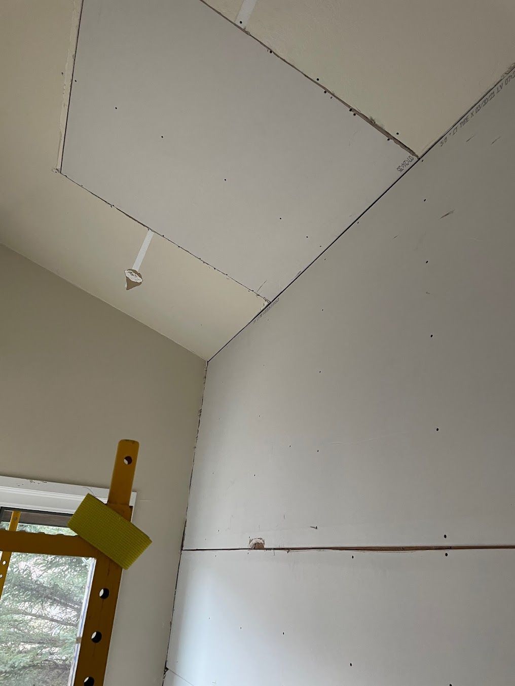 A bathroom under construction with a walk in shower and a door leading to another room.