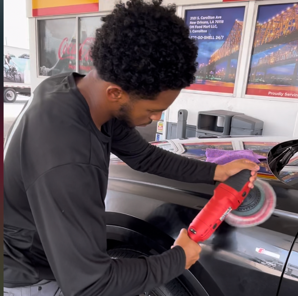 A man is polishing a car with a red machine