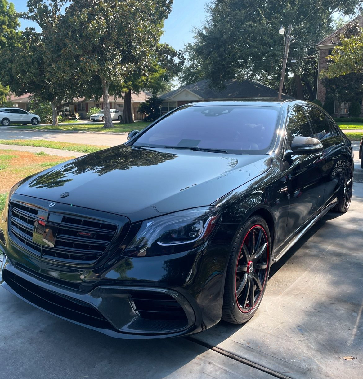 A black mercedes benz is parked in a driveway.