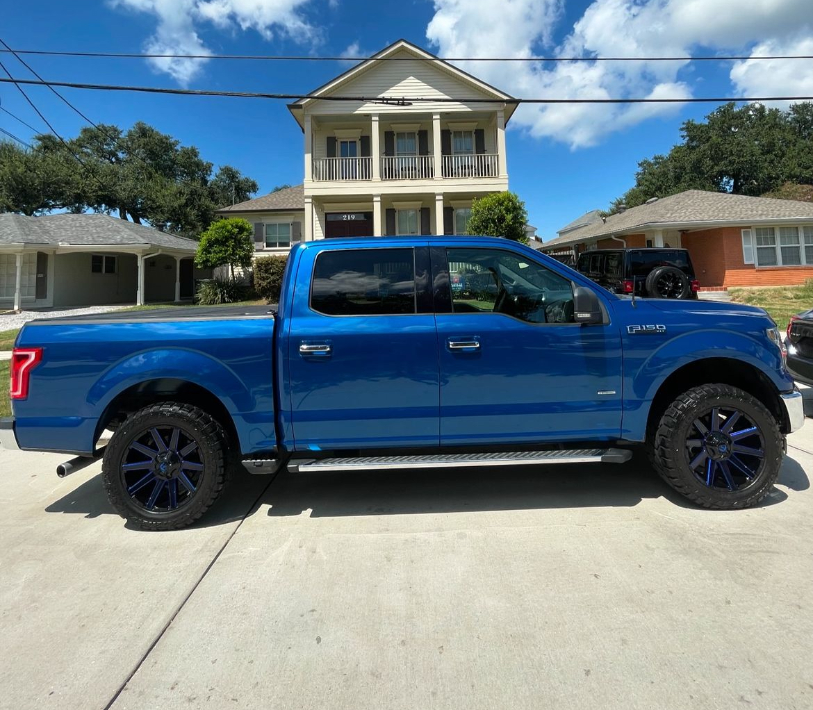 A blue truck is parked in front of a house