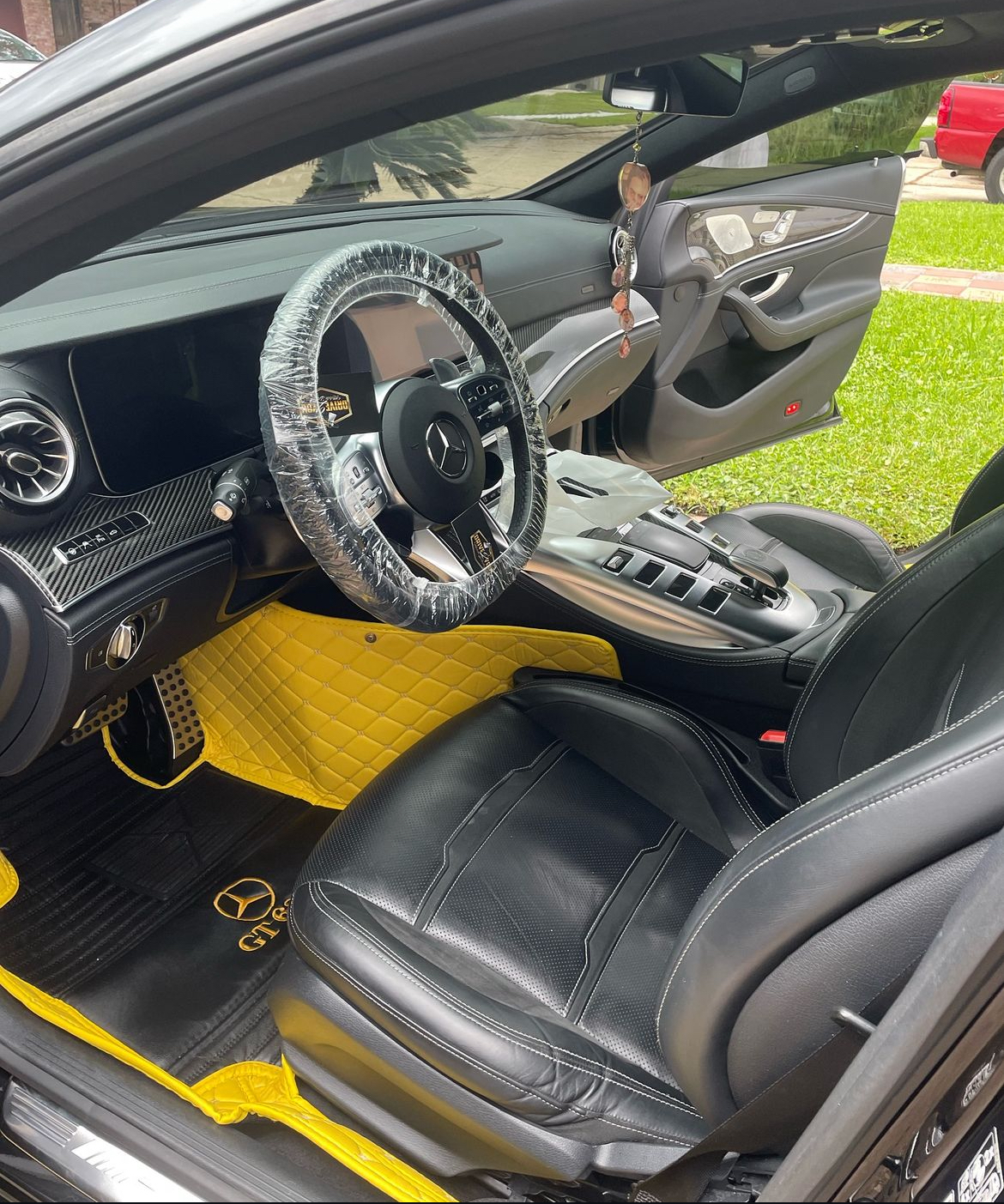 The inside of a black car with a yellow mat on the floor.
