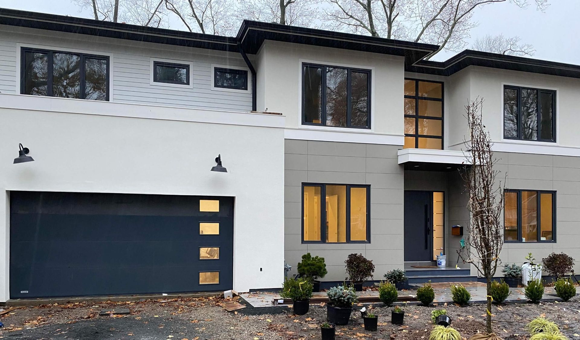 A large white house with a black garage door and a lot of windows.