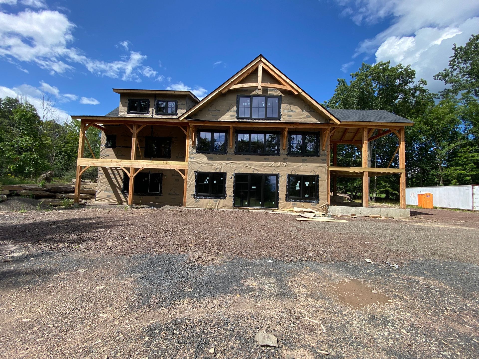 A large house is being built in the middle of a dirt field.