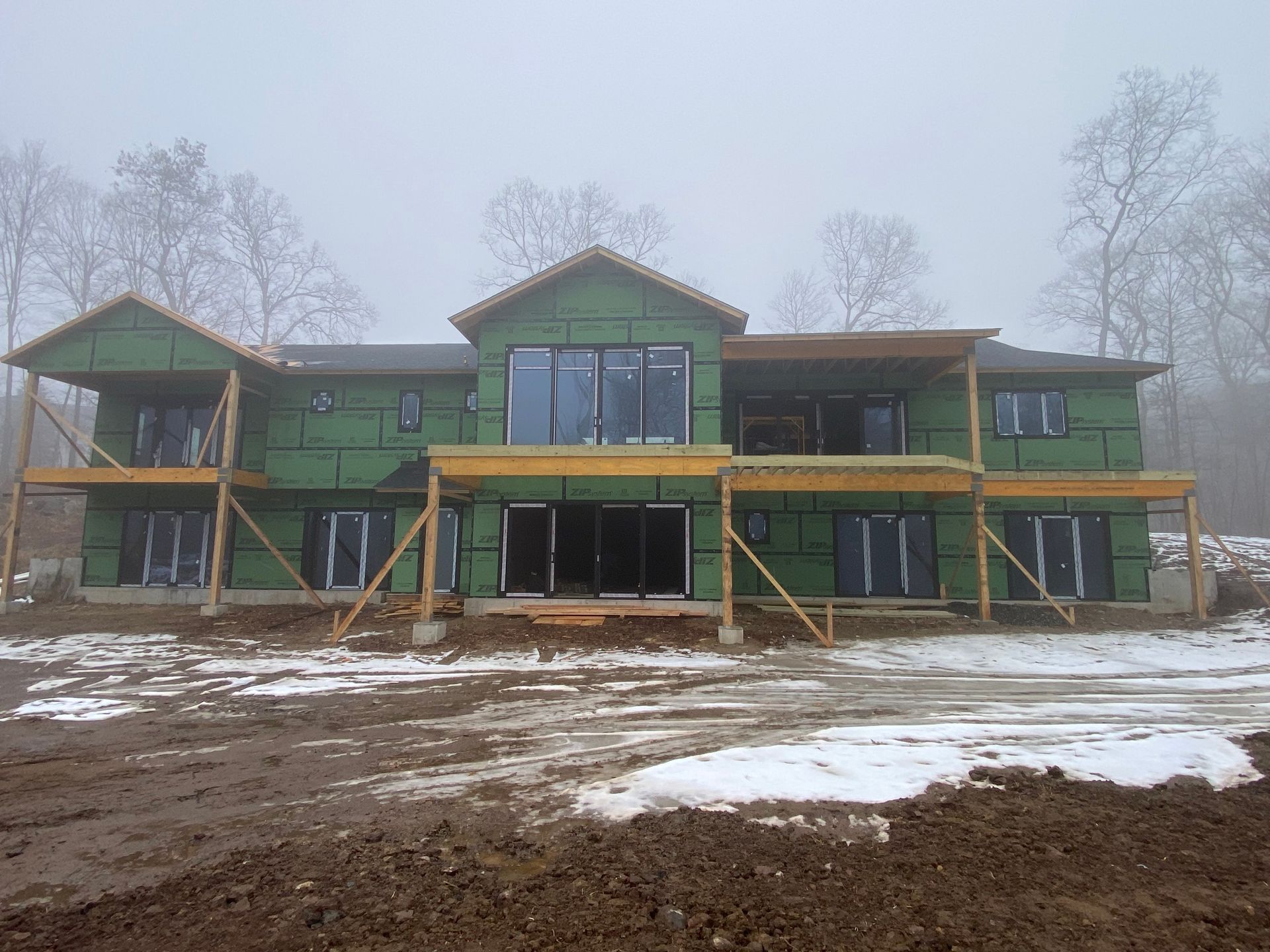 A large house is being built in the middle of a snowy field.