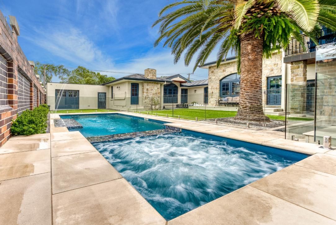 There is a large swimming pool in the backyard of a house.