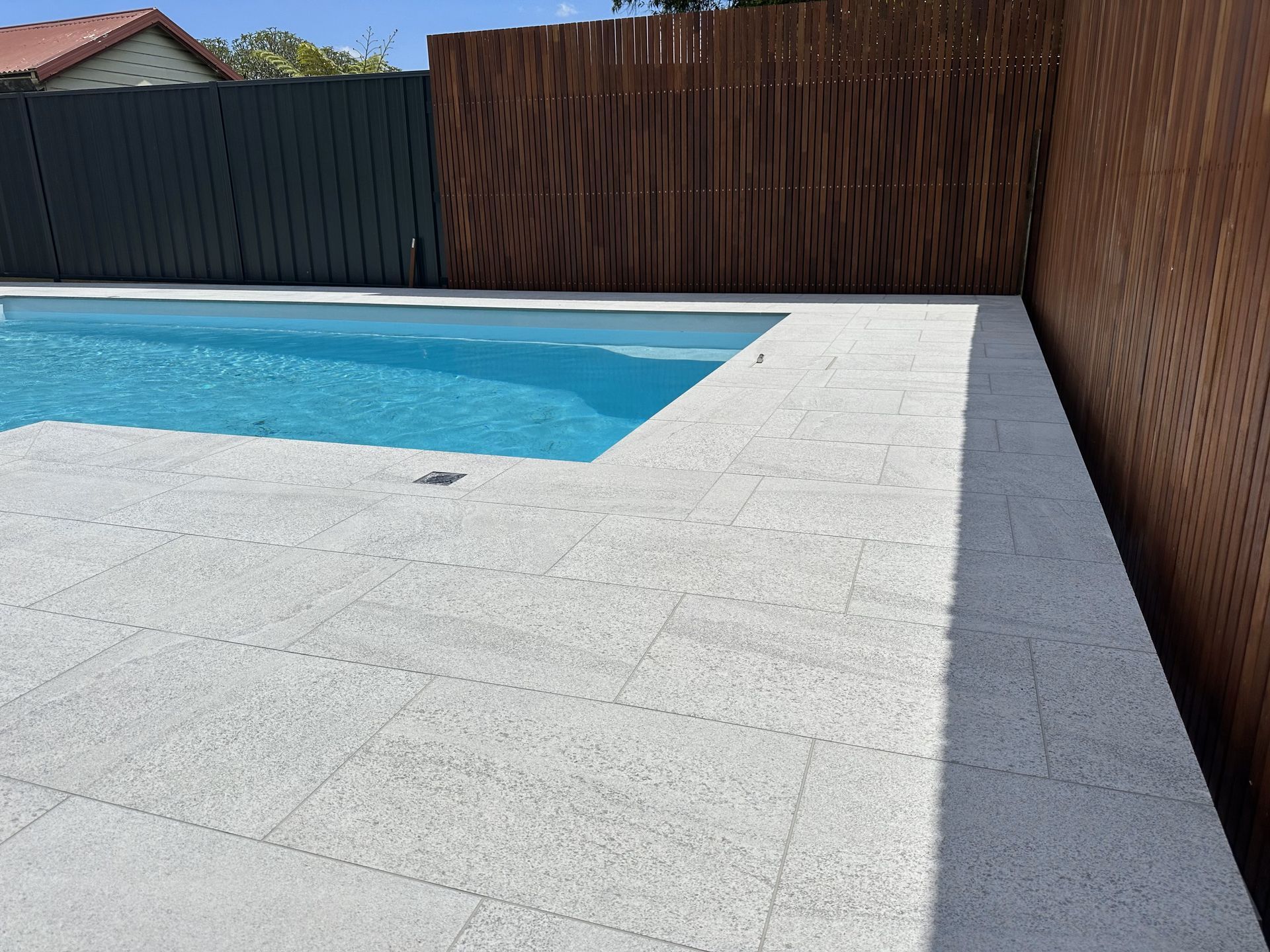 A swimming pool with a wooden fence in the background