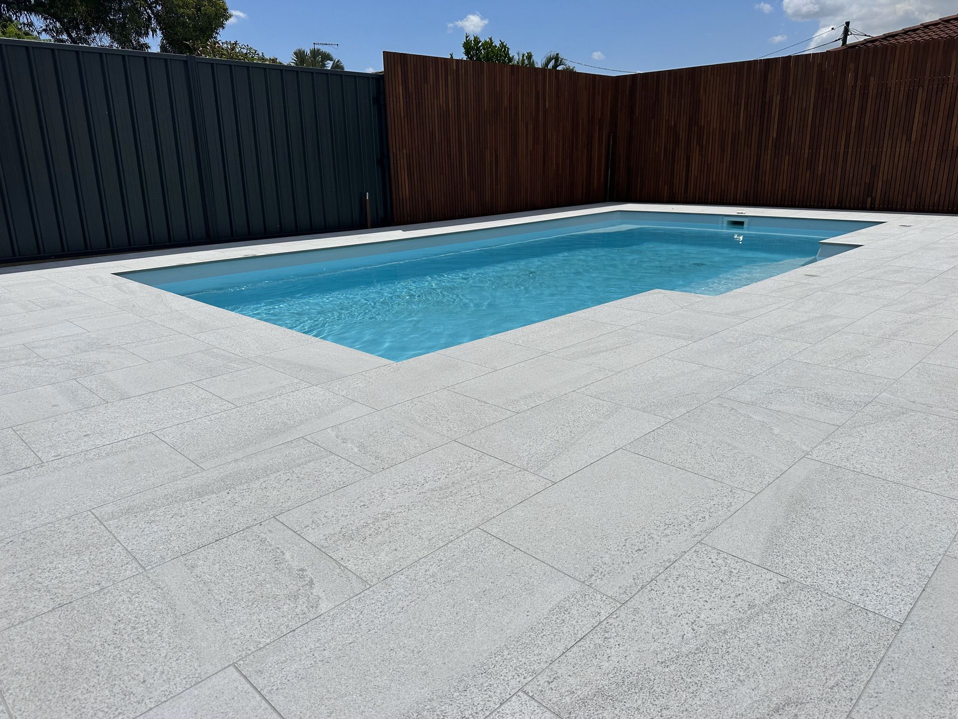 A large swimming pool with a wooden fence in the background